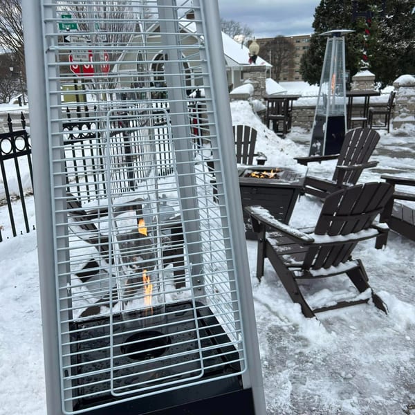 Outdoor patio at The Outsider with Adirondack chairs, fire pit, and patio heaters in the snow.