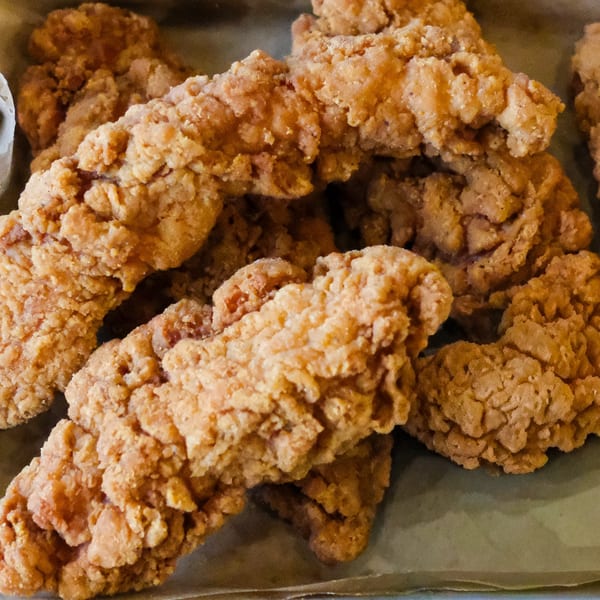 Close-up of golden-brown, crispy fried chicken tenders from The Outsider, a burger restaurant.