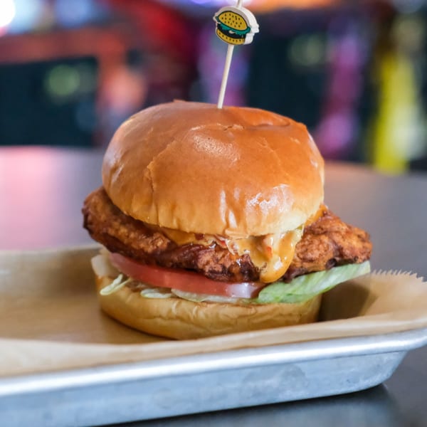 The Outsider's crispy chicken sandwich with lettuce, tomato, and special sauce on a bun.